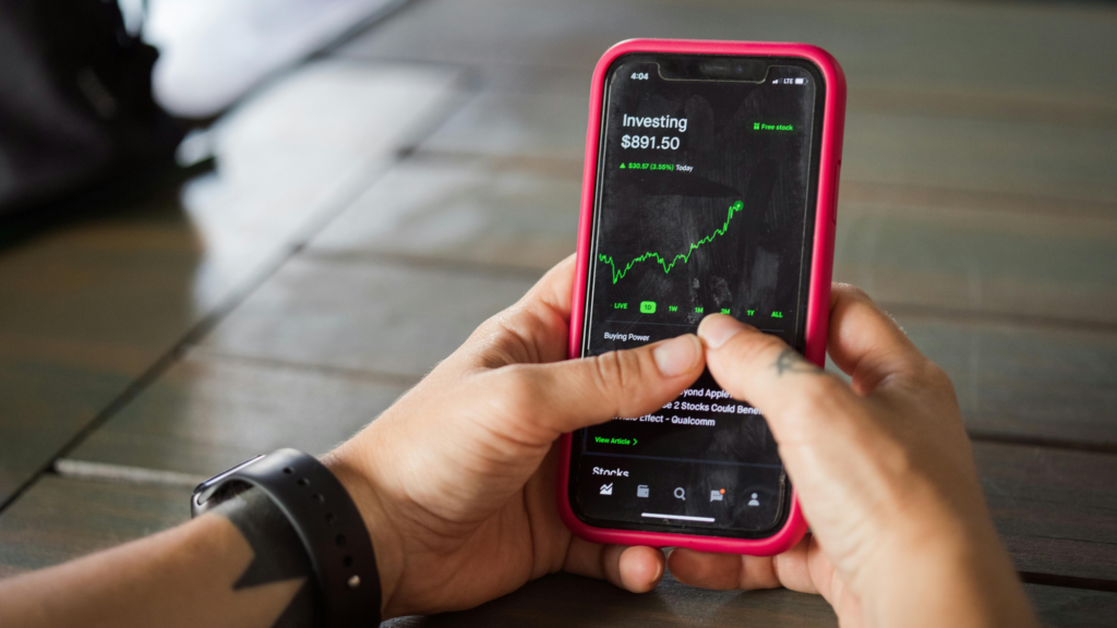 Person using an investment app on a smartphone, displaying stock market charts.