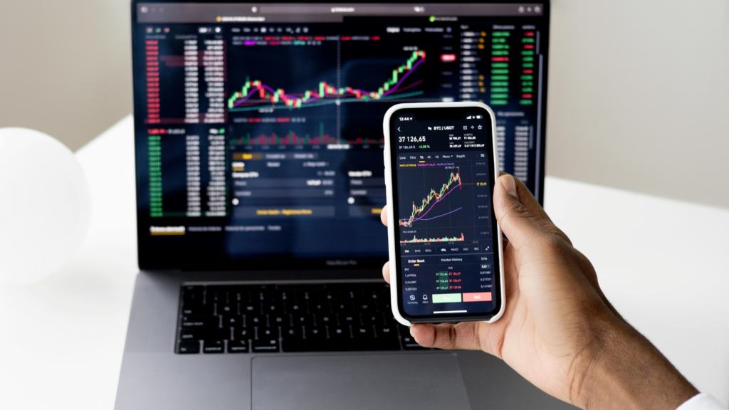 Real-time stock market analysis on a smartphone and laptop, demonstrating how investment apps enable passive income